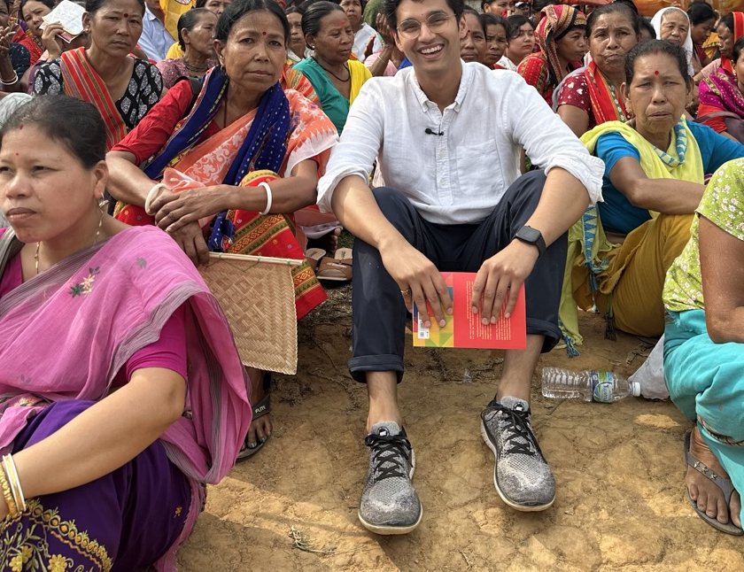 Sudhanshu seated on the ground among women at a community gathering